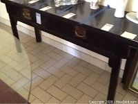 Wide shot of black Asian style sofa table showing two drawers with metal handles and the surface area.