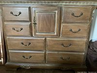 Front view of Lexington wooden dresser showing nine drawers and central cabinet door with metal handles, distressed finish and some scratches visible.