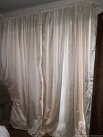 Front view of cream satin lined drapes hanging, showing smooth fabric and soft folds.