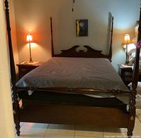 Front-facing view of the Thomasville queen poster bed showing headboard, footboard, and two nightstands with lamps on each side.