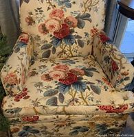 Front view showing floral rose pattern upholstery with red, pink, cream and yellow roses and green-blue leaves, cushioned seating and armrests.