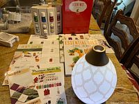 Full view of essential oil bottles in display holder, diffuser, and literature spread out on table.