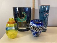 Photo of all four art glass vases together showing their shapes, colors, and designs.