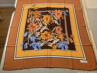 Full view of one vintage silk scarf with floral design and orange, yellow, blue, and brown colors
