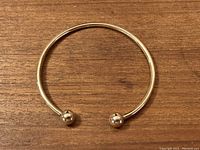 Photo showing the full small sized gold bracelet with open ends and rounded ball terminals.
