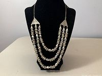 Full frontal view of necklace on display bust showing triple-strand beaded design.