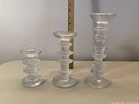 Full view of three Iittala Festiva candle sticks of varying sizes placed next to a ruler for scale.