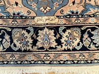 Close-up of woven signature on rug border with floral motifs