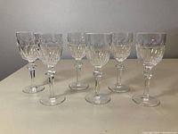 Front view of six crystal wine glasses in a row showing count and pattern.