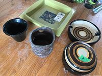 Photo showing five items: green square serving bowl with fruit image, black pottery cache pot, brown textured pottery cache pot, brown ashtray with concentric rings, and Italian trinket box with concentric rings.