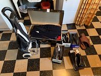 Wide view of vintage suitcase with folded clothing, collapsible buggy, and men's shoes arranged on floor