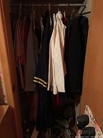 Closet view showing assorted women's clothing hanging inside including coats, jackets, and tops in multiple colors and fabrics