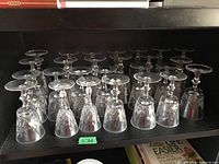 Shelf of inverted crystal glasses with etched cut patterns arranged neatly.