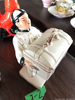 White ceramic male figurine holding lidded trinket box with a rabbit-shaped handle, showing overall detail.