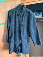 Front view of dark speckled long jacket with button closure and cross back button detail