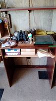 Wooden desk with various office decor items including binoculars, globe bookends, paper cutter, plaque, and pen holder