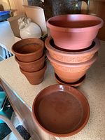 Full set of planter pots stacked and grouped with drainage plates included, showing wide view of lot contents