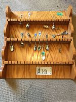 Full view of the wood display rack holding 14 souvenir spoons in three rows.