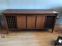 Front view of vintage wooden console stereo with lattice speaker covers on sides.