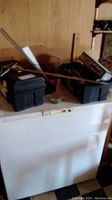 Black plastic toolbox on white surface with some tools inside and a long metal rod