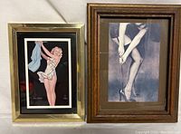 Two framed pinup girl prints side by side. Left is colorful pinup with gold frame. Right is black and white legs and heels with wood frame.