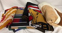 Four folded blankets stacked showing variety of colors and patterns including Southwest and military themes.