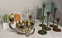 Photo of six brass candle holders, mercury glass bowl with brass candles, and three colored glass Partylite holders in foam packaging.