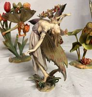 Photo showing one Dragonsite fairy figurine with arched back and detailed translucent wings, posed with arms extended back and standing on leafy base