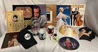 Wide shot showing the full contents of the collectible lot including albums, plaques, apparel, mugs, and memorabilia.