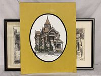 Three framed illustrated originals including one with yellow mat showing Haas - Lilienthal House as a Victorian-style house.