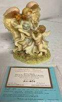Front view of the Seraphim Classics Forever Friends angel figurine alongside its certificate of authenticity showing numbering and artist signatures.
