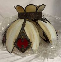 Photo showing the lamp's petal-shaped stained glass panels and decorative metal frame with red glass accents.