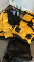 Photo showing two large yellow Coghlan's Dry Sack bags, black SealLine bag, and two cans of Nikwax products on the floor.