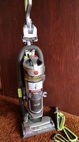 Front view of Hoover Air Lift upright vacuum cleaner showing handle, dirt canister, and attachments.