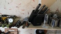 Photo of the kitchen tools including knives in block, stainless steel canisters, and utensils in a tray.