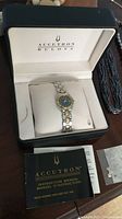 Watch displayed inside original white and black Accutron Bulova presentation box with instruction manual and extra link visible