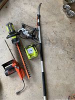 Photo showing Ryobi cordless hedge trimmer, charger, Remington chainsaw, and Trail Blazer pruning saw with manual extension.