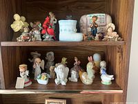 Two shelves with a mix of animal, angel, children, bird, and boot figurines on a wooden shelf unit