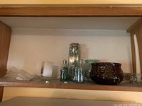 Glass containers with decorative glass stones, marbles, small ceramic pot on shelf