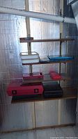 Multiple toolboxes on wooden shelves against an insulated wall, various colors and sizes, stacked and closed