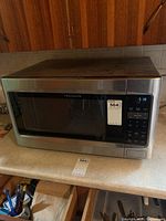 Front view of stainless steel Frigidaire microwave with glass door and digital display showing 5:18 PM.