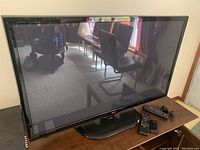 Front view of Phillips 45-inch LG flat screen TV on wood surface with remotes and cords.