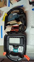Top view of Black and Decker Mouse sander inside black plastic case with power cord and sanding sheets.