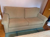 Full front view of beige sleeper sofa seating area and back cushions
