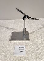 Front and side views of vintage Thompson fly tying vise, showing pedestal base and adjustable clamp mechanism with screw tightening knob.