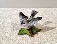 Front view of the Lenox Tufted Titmouse porcelain bird sculpture showing the bird with raised wings perched on a leafed branch.