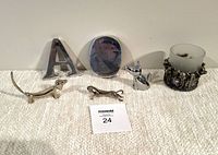 Front view of lot showing a chrome letter A, circular ampersand paperweight, three chrome animal figurines (two dog shapes, one fox), and a pewter pig candle holder with frosted glass.