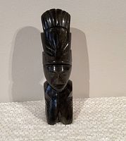 Front view of the polished obsidian stone Aztec figure sculpture showing detailed facial and headdress features.