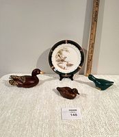 Overall lot view showing three wooden duck carvings and the Noritake Keltcraft Ireland collector plate with ruler for scale