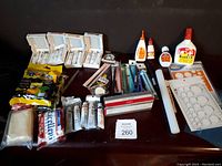 Wide shot showing full lot layout with sculpting tools, adhesives, paint tubes, scissors, rolling pin, and clay block